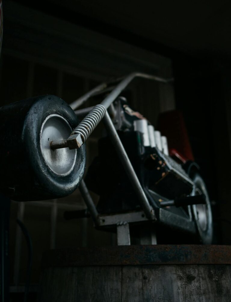 Detailed view of a vintage metal motorbike model in a dark workshop setting.